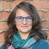 Headshot of smiling person with long hair and glasses.