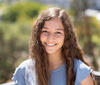 Headshot of smiling person with long dark hair.