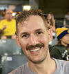 Headshot of smiling person with short dark hair and a mustache.