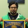 Photo of person with short dark hair, glasses, and facial hair holding a "California" banner in blue and gold.