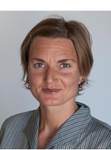 Headshot of a person smiling slightly with medium-short light-colored hair and a collared shirt.