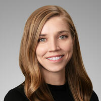 Headshot of a smiling person with long medium-colored hair.